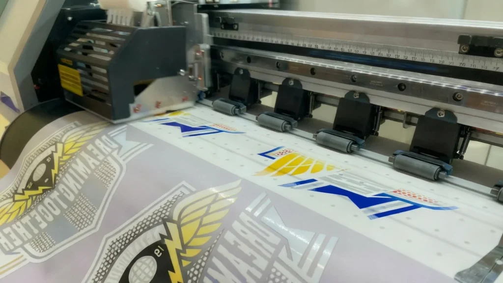 High-quality embroidery design services in progress with precision cutting machine creating custom logo transfers for apparel branding.